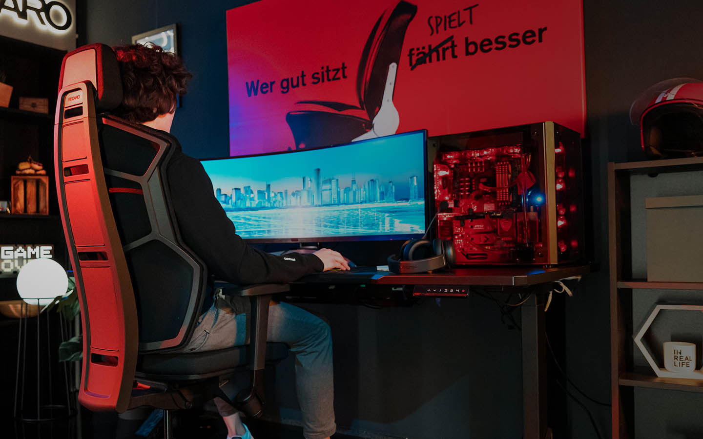 Gamer sits on the new RECARO Aer Ruby Red in front of his monitor. 